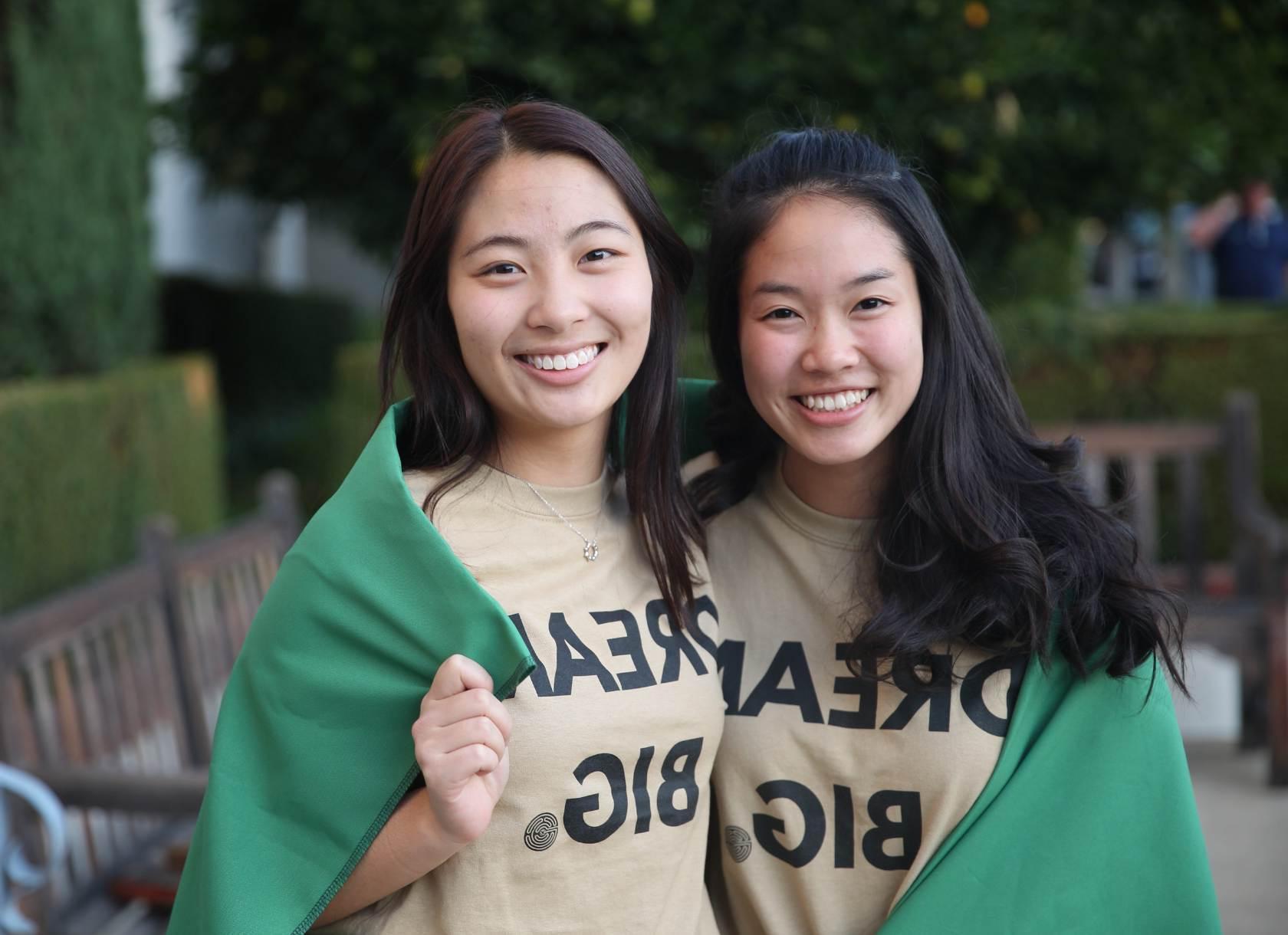 两名学生穿着印有“远大梦想”字样的衬衫，围着斗篷